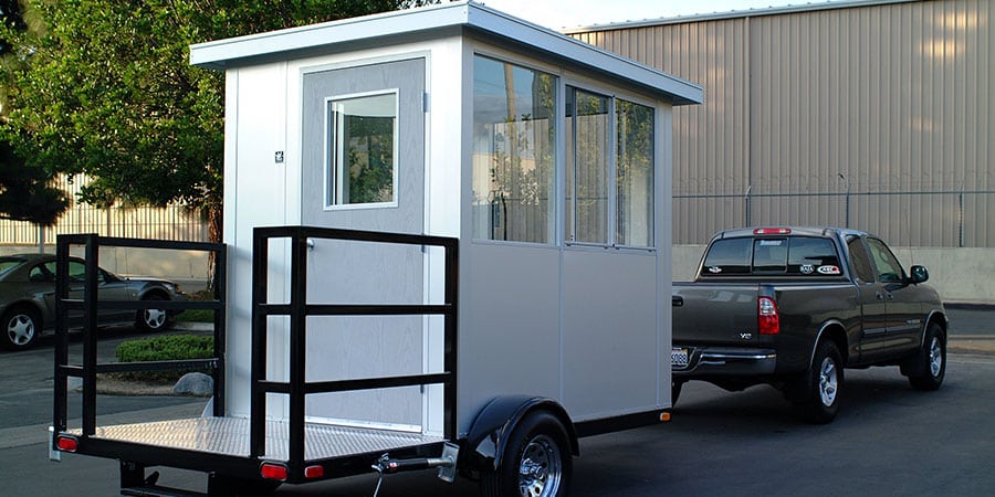 A modular guardhouse trailer being pulled by a truck.