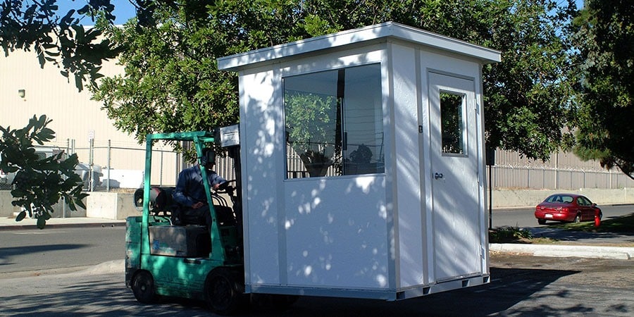 A forklift moving a modular guard house.