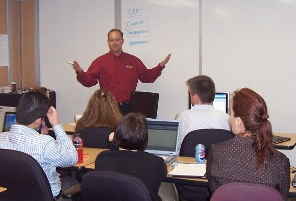 A teacher in front of a whiteboard in a modular training room.