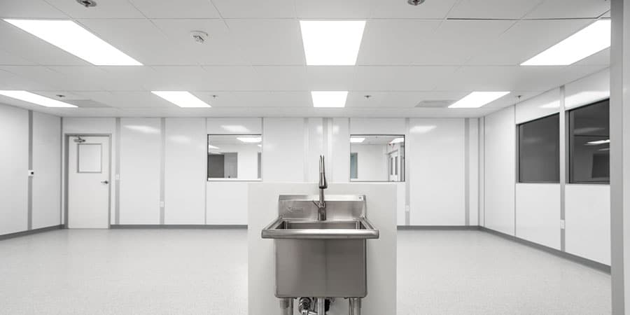 Allied Modular white room interior featuring clean non-porous wall panels, recessed lighting, stainless steel wash station, and observation windows