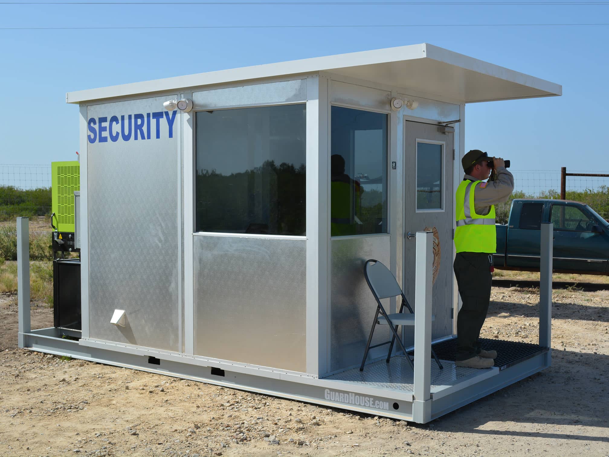 An operational guard shack, with a security guard looking out using a pair of binoulars.