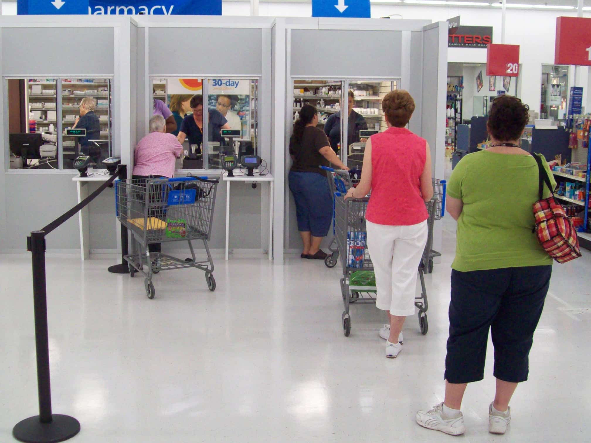 Modular pharmacy checkout counters with customers waiting in line, featuring prefabricated enclosures by Allied Modular.