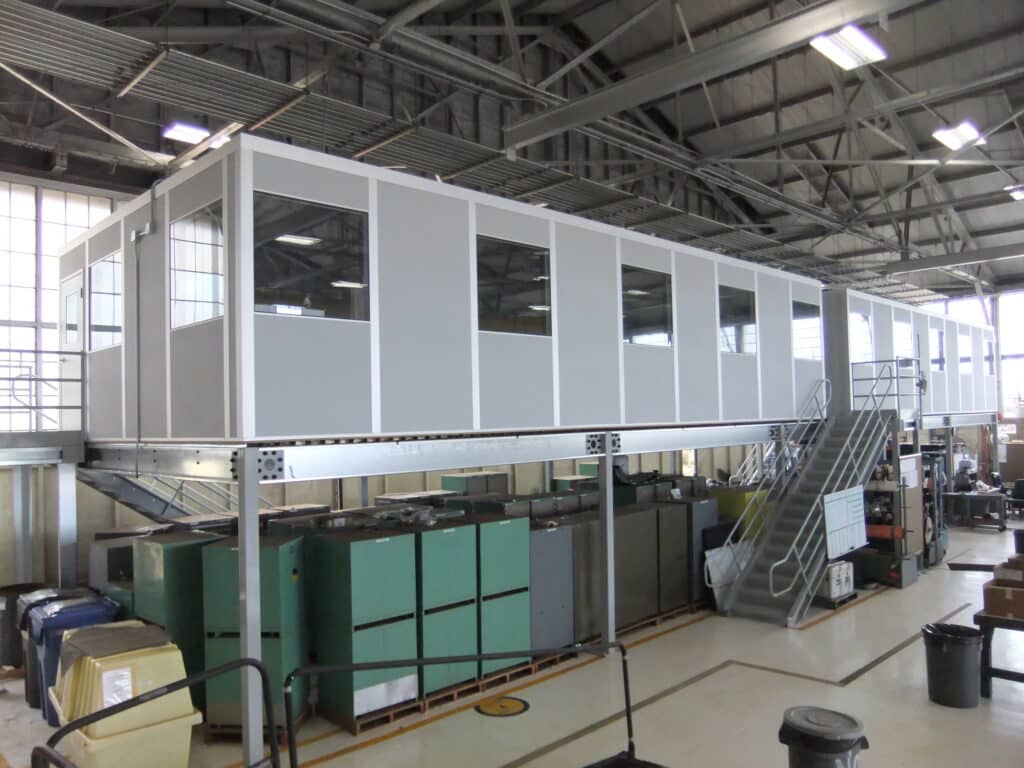 A gray modular office on top of a freestanding mezzanine.