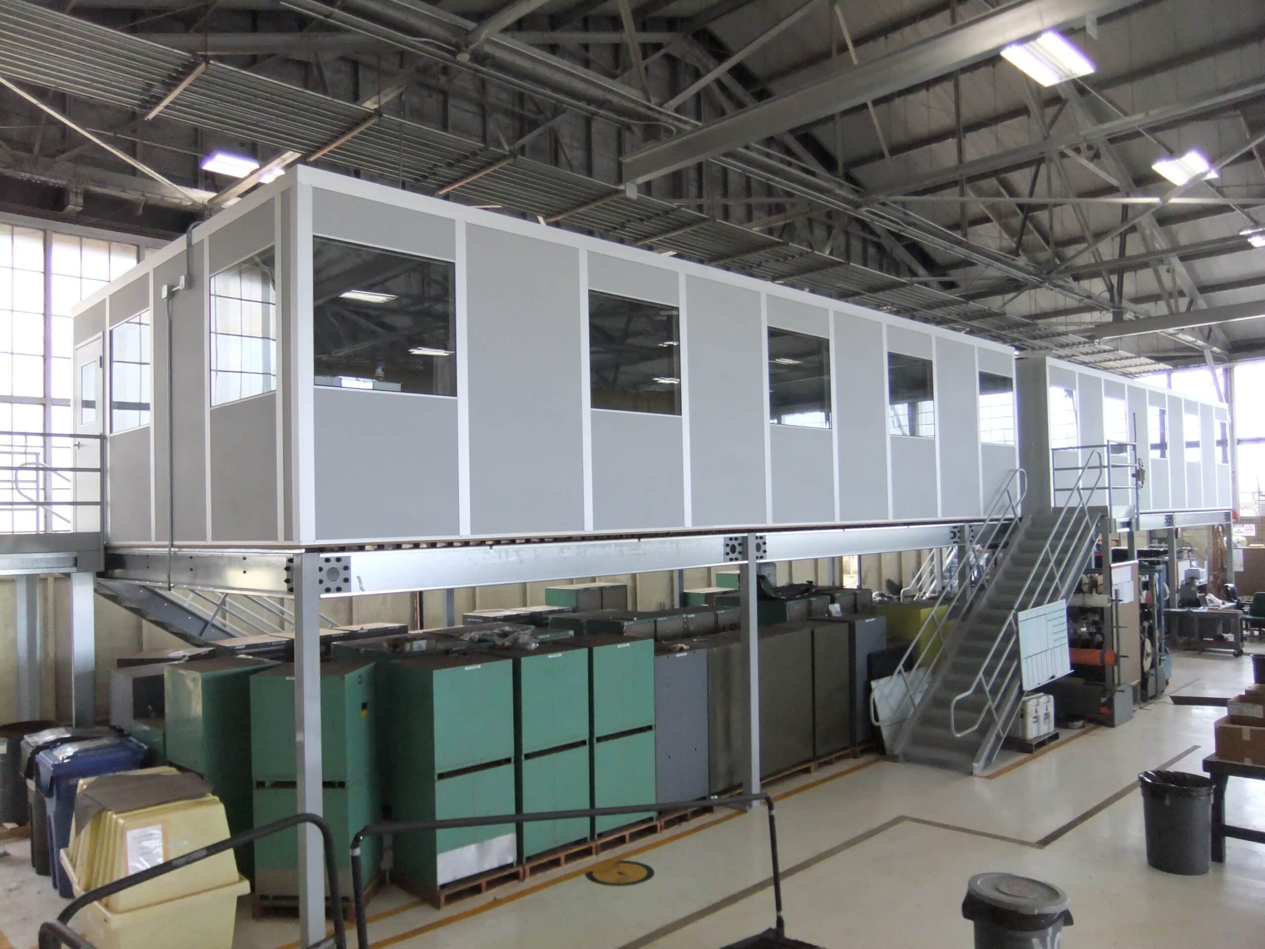 A gray modular office on top of a freestanding mezzanine.