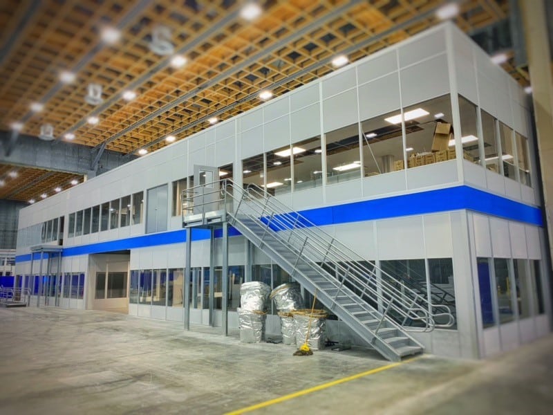 A modern, industrial-style office space with an external staircase leading to a second-floor area inside a large warehouse.