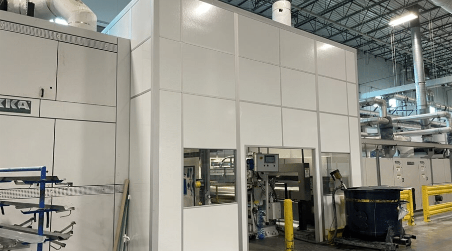 A large modular machine enclosure in a warehouse, designed to isolate machinery and reduce noise and emissions.