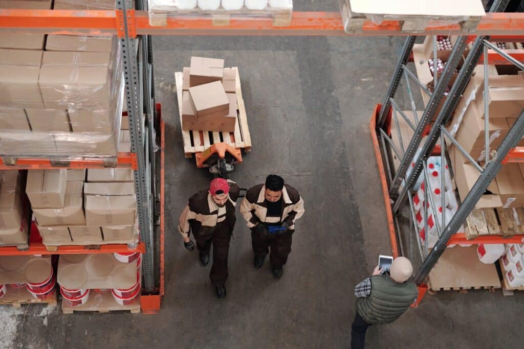 Warehouse workers navigating through organized shelving units with clear pathways and neatly stacked boxes.