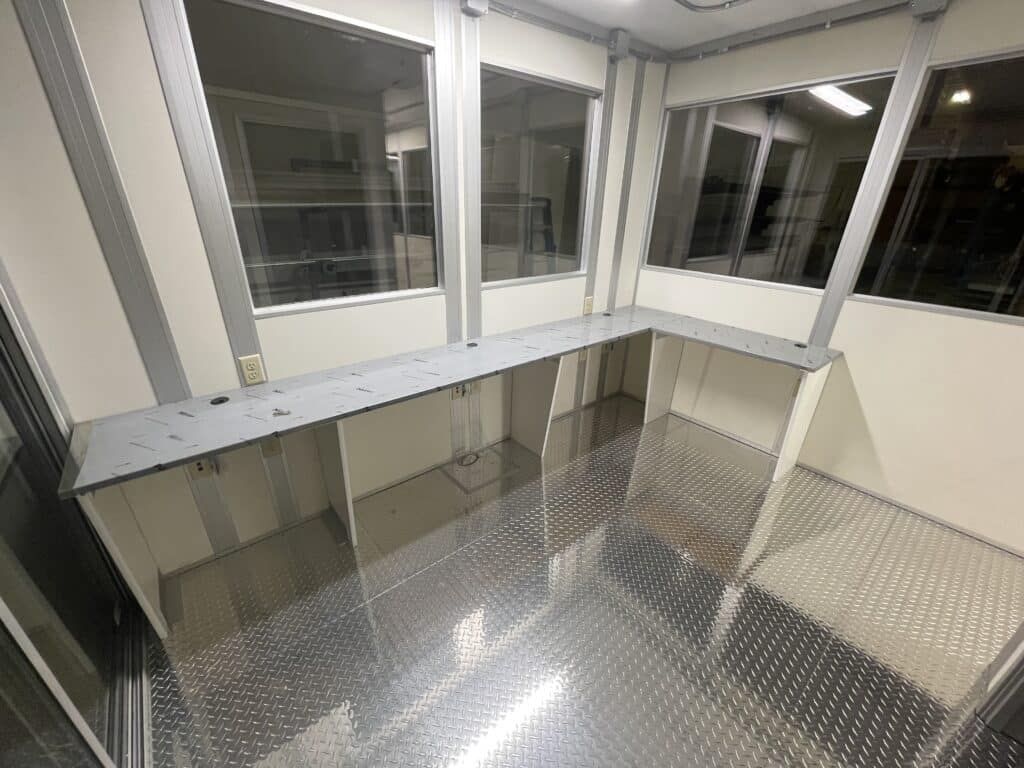 Interior of a modular scale house featuring a durable metal floor, long counter space, and large windows, providing an efficient workspace for managing weighbridge operations.