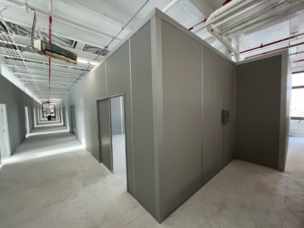 Industrial workspace featuring freestanding walls used to create separate rooms and work areas, showcasing a modular design for quick and flexible space division.