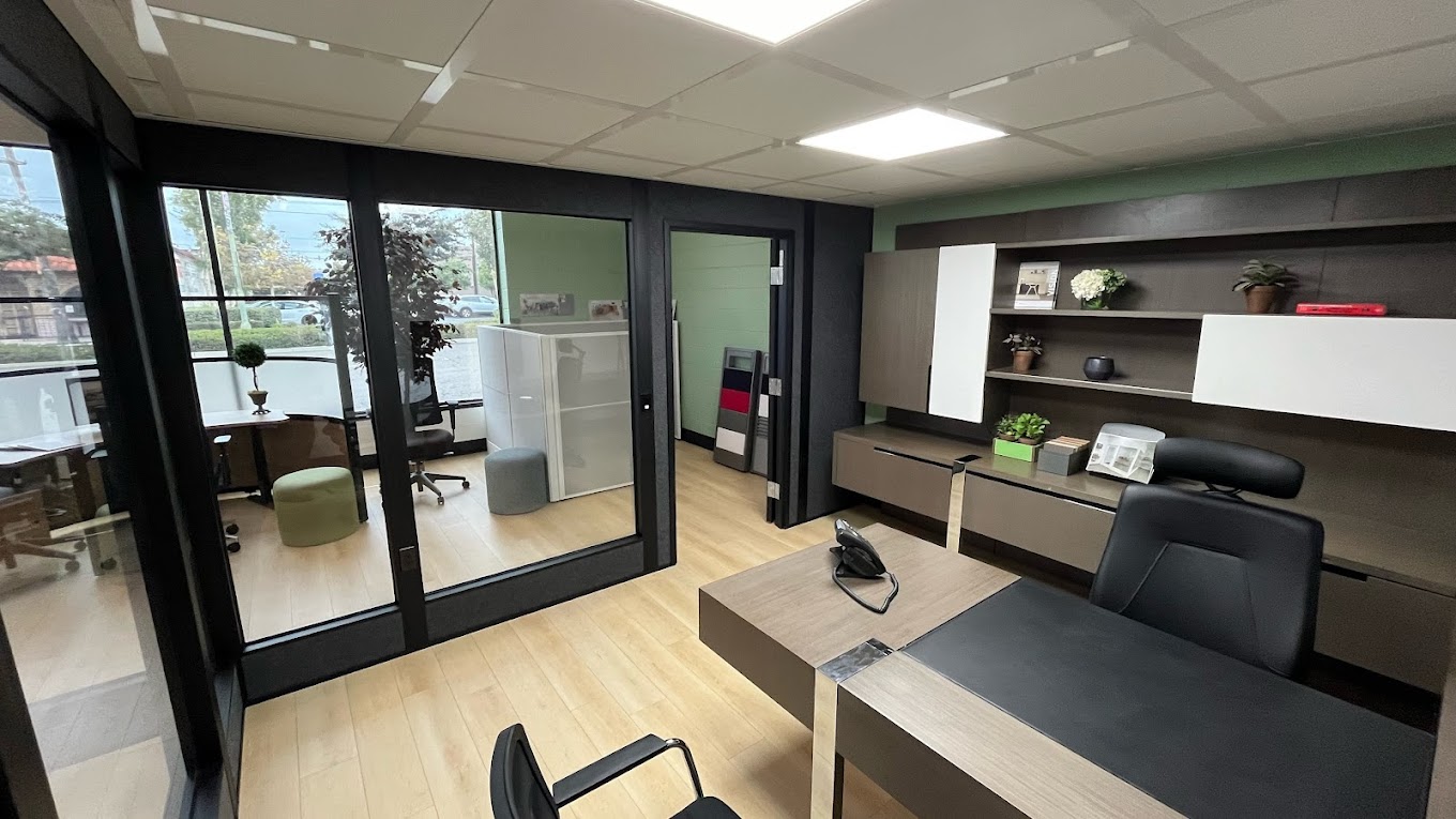 Modern office space featuring freestanding walls with full glass partitions, providing a clear division between the workspace and meeting area while maintaining an open, inviting atmosphere.