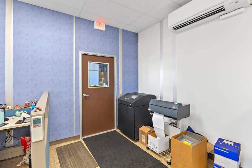 Spacious conference room with modern furnishings inside a modular office building, featuring large windows and a wall-mounted TV.