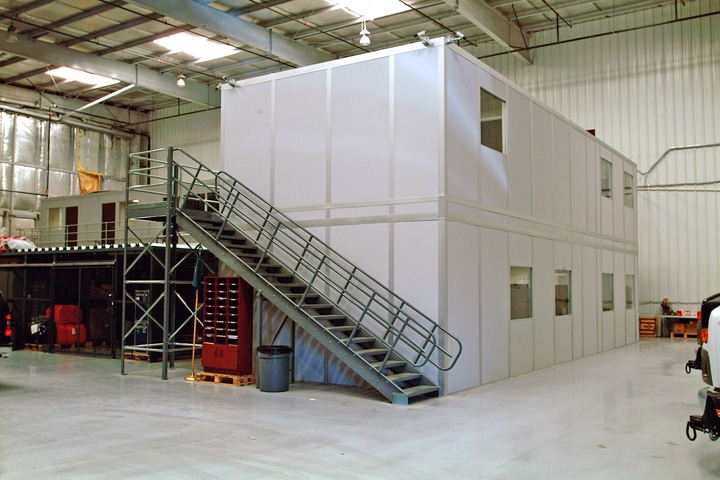 Two-story modular office building by Allied Modular, installed inside a warehouse with an external metal staircase.