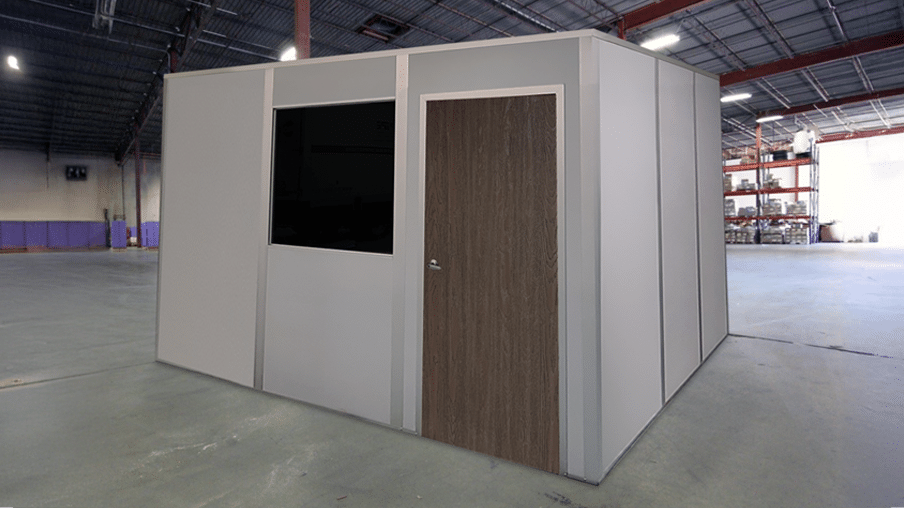 A quick-ship modular office by Allied Modular, installed inside a warehouse. The structure features a solid door, a window, and durable panel walls, providing a fast and efficient workspace solution.