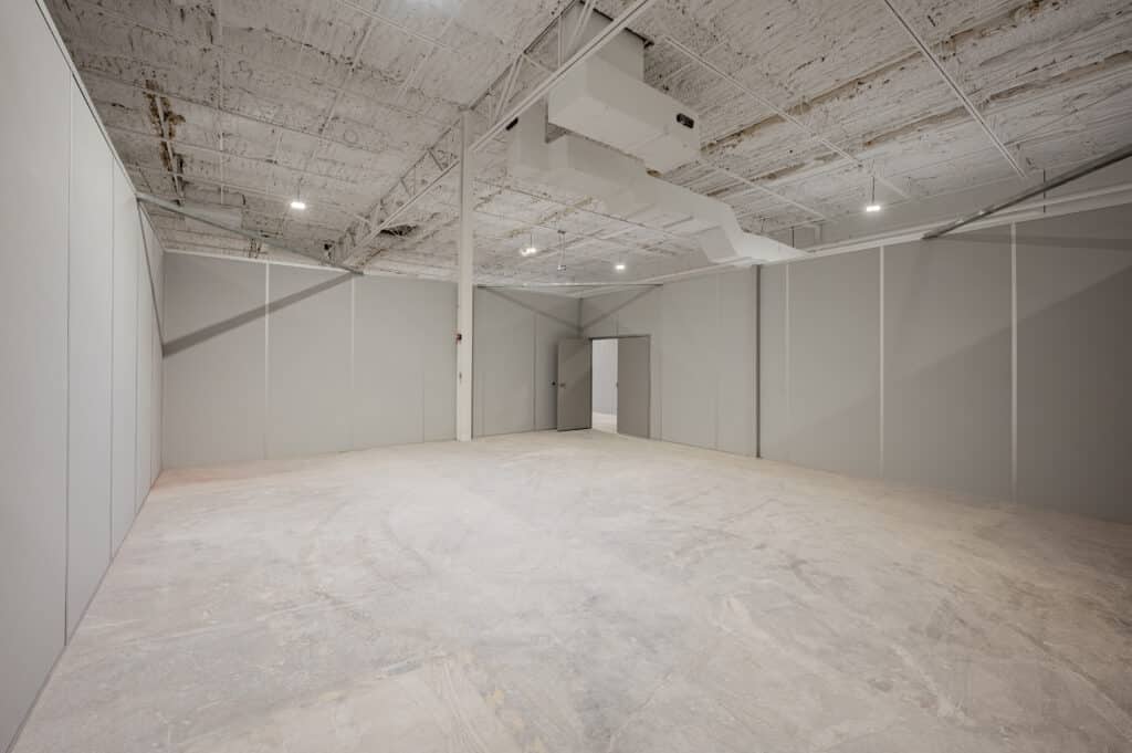 An empty warehouse space featuring modular wall dividers, creating a defined and flexible layout for storage or workspace customization.