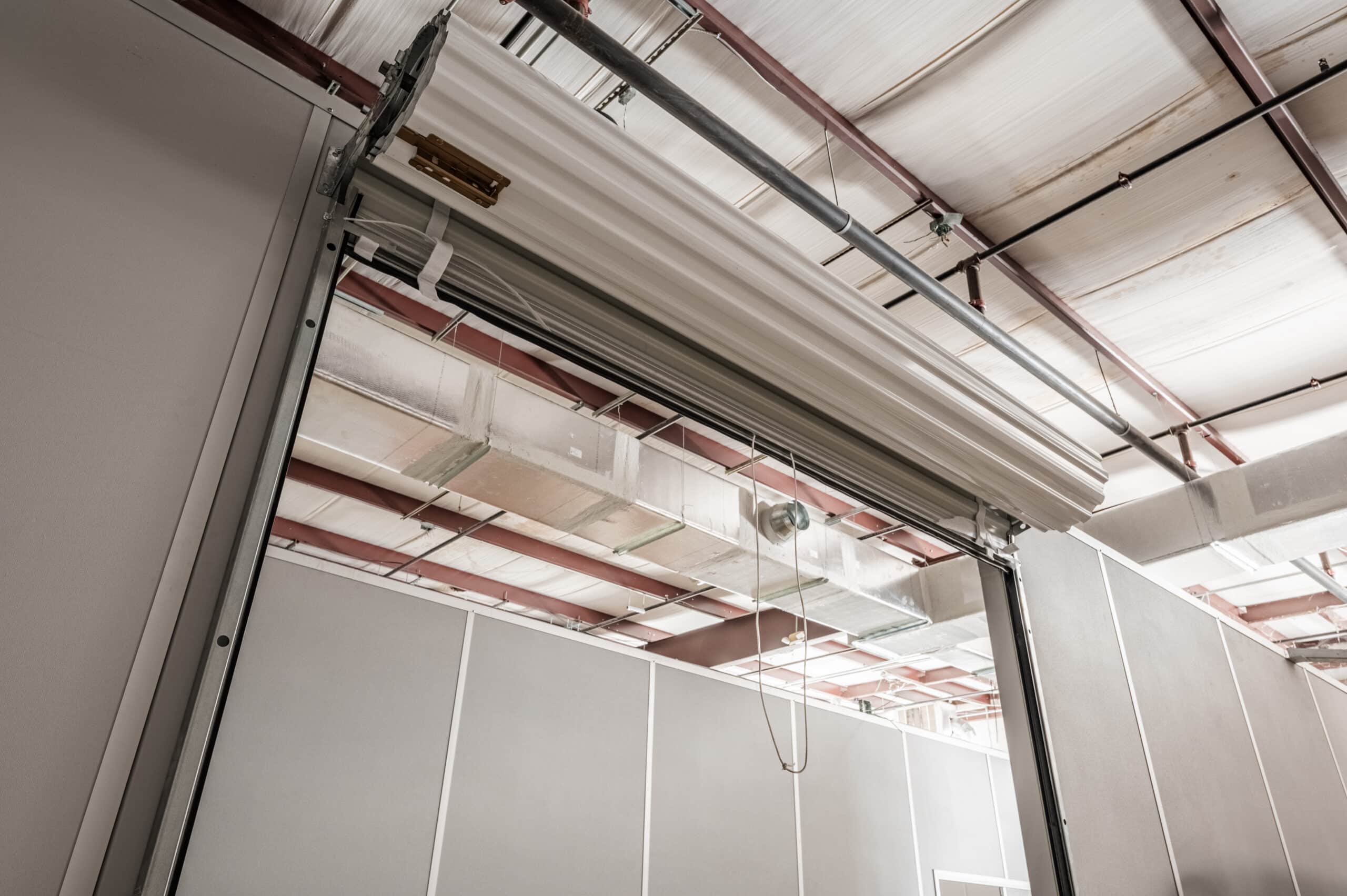 An interior shot of an Allied Modular modular enclosure featuring clean, prefabricated wall panels, steel support beams, and an overhead roll-up door. The factory-built, reusable wall systems shown here are the type of modular construction that can earn up to 25 points toward LEED certification.