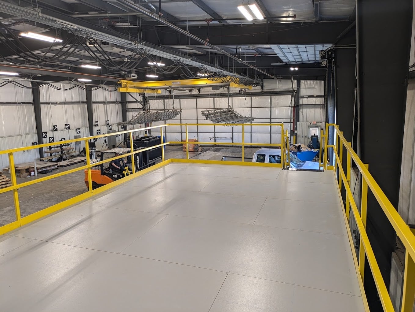 Allied Modular pallet racking mezzanine platform installed in a warehouse with yellow guardrails and overhead equipment.