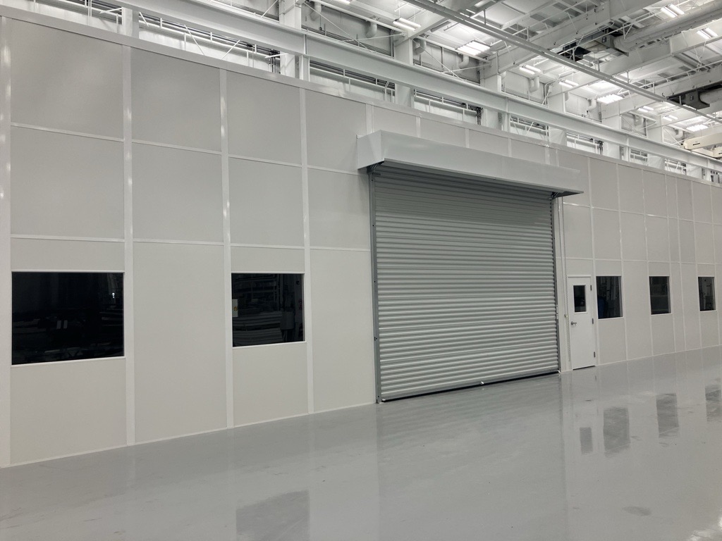 Large sustainable modular building with roll-up door and windows, built by Allied Modular inside an industrial facility.