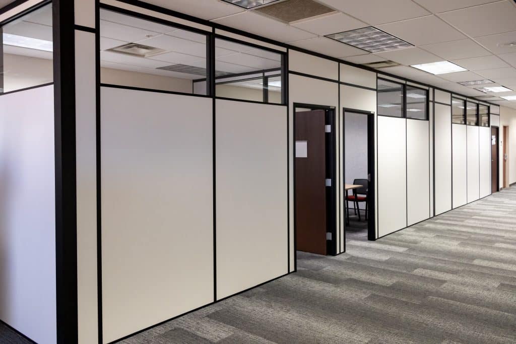 Office hallway with modular partition walls and private offices built by Allied Modular using black-framed white panels and upper glass inserts.