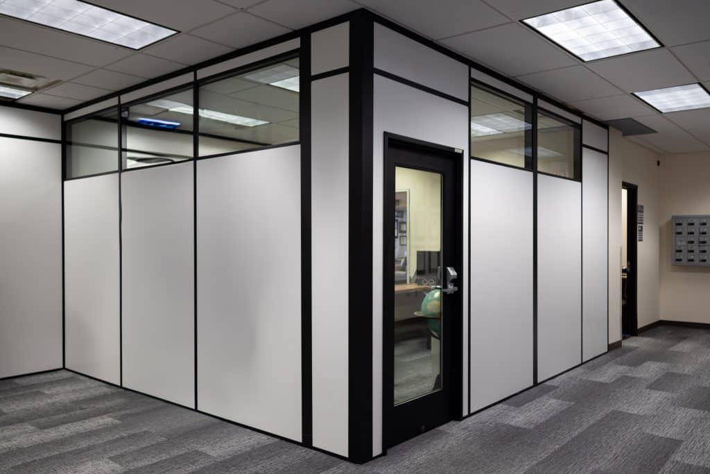 Modular office enclosure built by Allied Modular featuring black-framed panels with glass upper sections and a glass door.