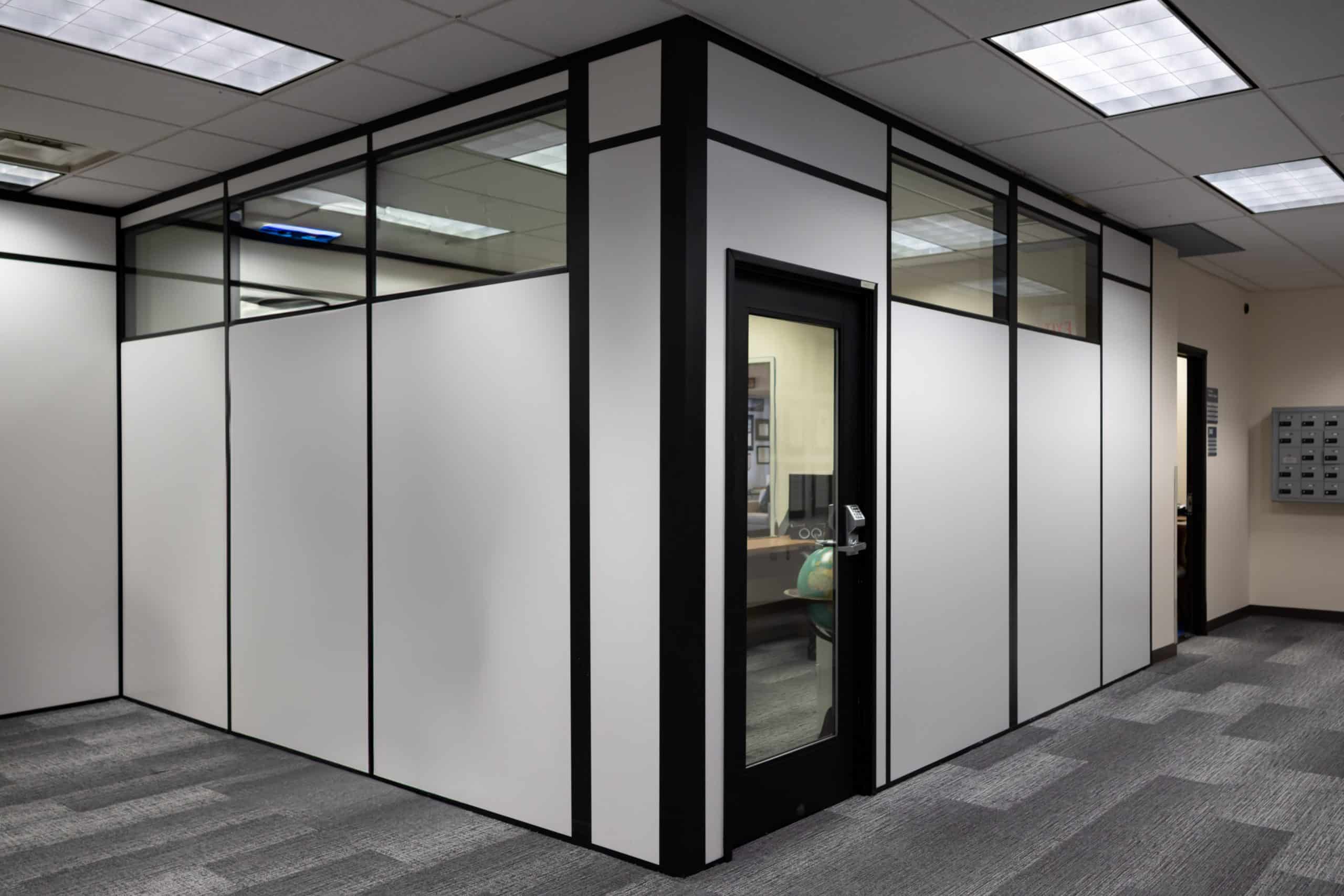 Modular office enclosure built by Allied Modular featuring black-framed panels with glass upper sections and a glass door.