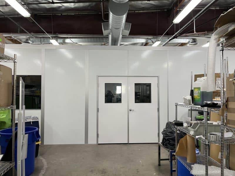 White modular laser welding enclosures by Allied Modular with double doors and overhead ventilation ducting.